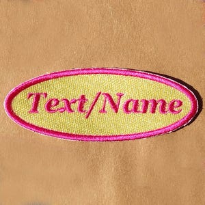 May include: A yellow oval-shaped patch with a pink border. The text "Text/Name" is embroidered in pink on the patch.