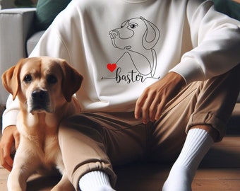 May include: A white sweatshirt with a line drawing of a dog and the text "I love Baster" in black with a red heart. A person is wearing the sweatshirt and sitting with a golden retriever dog.