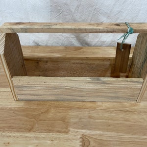 May include: A wooden box with a handle, made from reclaimed wood. The box has a natural wood finish and is perfect for storing small items.