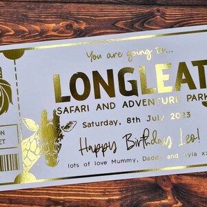 May include: A gold foil ticket for Longleat Safari and Adventure Park, with the date Saturday, 8th July 2023. The ticket says "You are going to... Longleat Safari and Adventure Park" and "Happy Birthday Leo!" with a message "lots of love Mummy, Daddy and Ayla xxx".