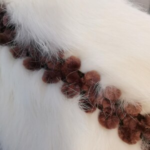 May include: White faux fur fabric with a brown trim of fluffy pom-poms.