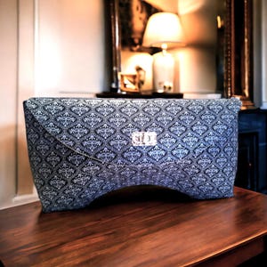 Cartera de mano de piel de ante genuino, diseño exclusivo con forma anatómica para llevar en la mano, con cierre de broche plateado.