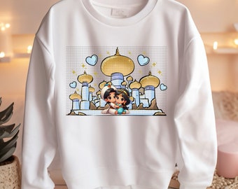 May include: White sweatshirt with a cartoon image of Aladdin and Jasmine in front of the palace in Agrabah. The image features blue hearts and gold accents.