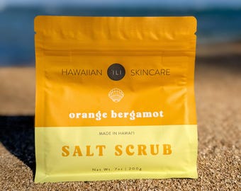 May include: A bright yellow and cream-colored bag of Hawaiian skincare salt scrub. The bag features the text "HAWAIIAN ILI SKINCARE", "orange bergamot", and "SALT SCRUB". The net weight is 7 oz (200g).