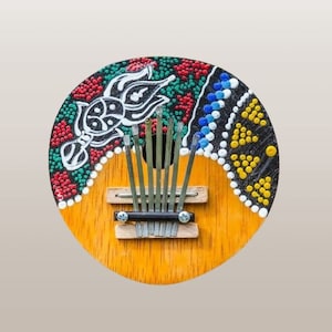 May include: A wooden hand-painted kalimba with a colourful design featuring a black, white, red, green, blue and yellow pattern. The kalimba has eight metal tines.