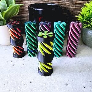 以下が含まれることがあります： プラスチック製のカラフルな螺旋状のフィジェットおもちゃ6個。おもちゃは白い表面に一列に並んでいます。おもちゃは黒、緑、紫、ターコイズ、赤です。