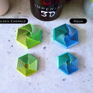 May include: Four hexagonal coasters with a spiral design. Two coasters are green and blue, and the other two are a gradient of green and blue. The coasters are labeled "Golden Emerald" and "Aqua".