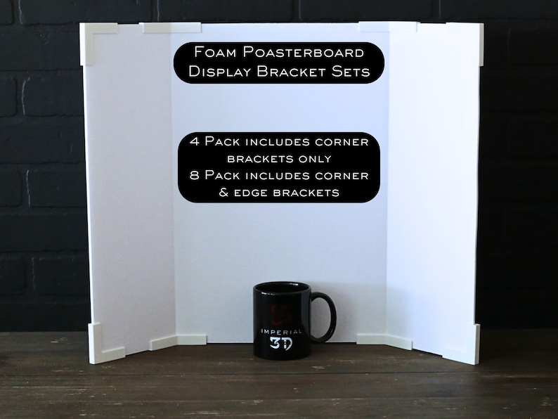 Op de afbeelding: Witte schuimplaat display achtergrond met hoek- en randbeugels. De tekst op de plaat luidt "Foam Poasterboard Display Bracket Sets 4 Pack Includes Corner Brackets Only 8 Pack Includes Corner & Edge Brackets". Een zwarte mok met de tekst "Imperial 3D" staat voor de achtergrond.