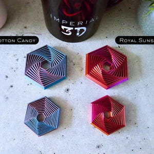 May include: Four hexagonal coasters with a swirling pattern. The coasters are in the colors cotton candy, royal sunset, blue, and red.