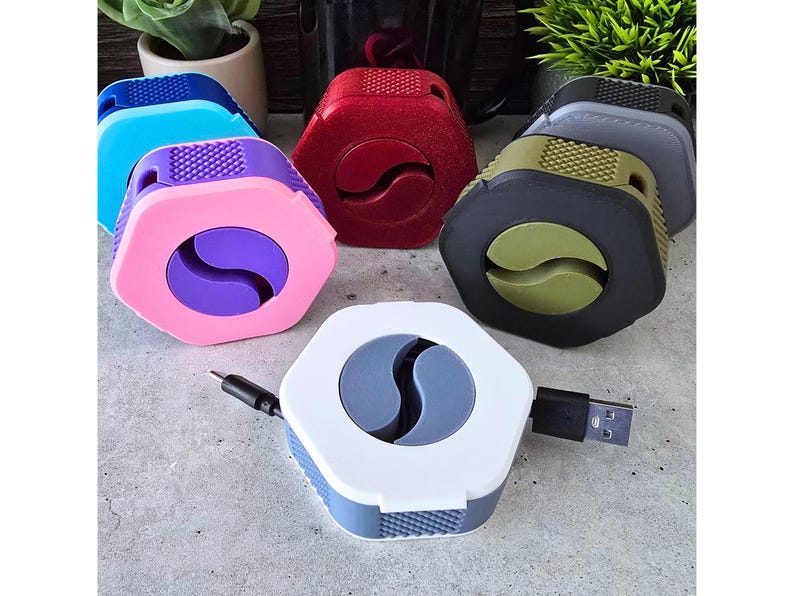 K&ouml;nnte beinhalten: Ein Set mit sechs Kabelorganisatoren in verschiedenen Farben, darunter Lila, Rot, Gr&uuml;n, Blau, Grau und Wei&szlig;. Jeder Organisator hat ein einzigartiges Design mit einem Yin-Yang-Symbol und einem Loch f&uuml;r ein Kabel.