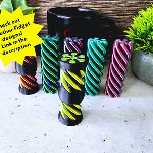 May include: Five colorful fidget toys made of plastic. The toys are in a spiral shape with different colors, including green, purple, and red.  Check out our other Fidget designs! Link in the description.