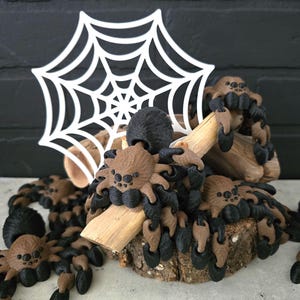 May include: A Halloween-themed decorative display featuring multiple brown and black spiders crawling on a wooden log and a white spider web. The spiders have detailed features and are arranged on a rustic wooden base.