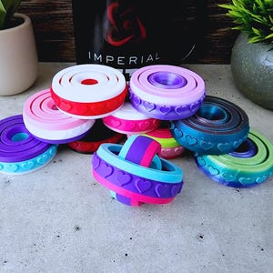 May include: A collection of colourful, multi-layered, heart-shaped fidget toys. The toys are made of a soft, pliable material and are designed to be squeezed and manipulated. The toys are a great way to relieve stress and anxiety.