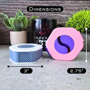 K&ouml;nnte beinhalten: Zwei runde Beh&auml;lter mit Deckeln. Der Beh&auml;lter links ist grau mit einem wei&szlig;en Deckel und hat einen Durchmesser von 7,6 cm. Der Beh&auml;lter rechts ist rosa mit einem violetten Wirbelmuster und hat einen Durchmesser von 7 cm.