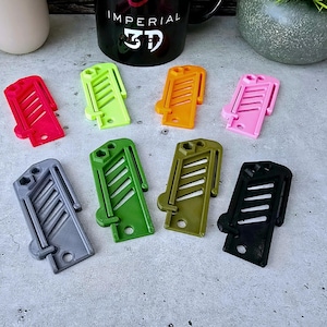 May include: Eight different colored plastic clips, each with a unique design. The clips are arranged in two rows of four. The clips are all about 2 inches long and 1 inch wide.