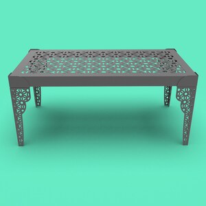May include: A gray metal table with a decorative, laser-cut design on the top and legs. The table has a rectangular shape and is sitting on a turquoise background.