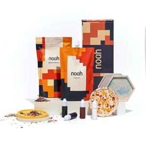 Peut inclure: Un ensemble de sous-verres en terrazzo de style coloré avec un plateau assorti, un sac de poudre de terrazzo, une bouteille de liquide de terrazzo et quatre petits flacons de peinture. L'emballage porte le mot "noah" en caractères gras.