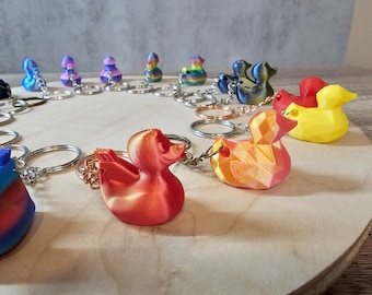May include: A collection of colorful rubber duck keychains, each with a different design and color. The keychains are arranged in a circle on a wooden surface.