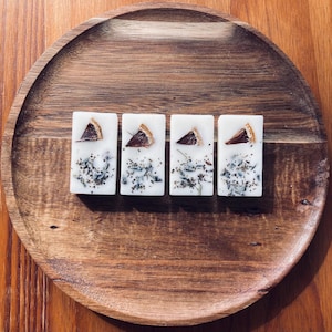 May include: Four white wax melts with dried orange slices and dried lavender flowers on a wooden tray.