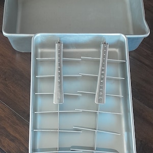 May include: A silver metal ice cube tray with two removable handles labeled "Quick-Kube" and a handle on the front that says "FRIGIDAIRE".