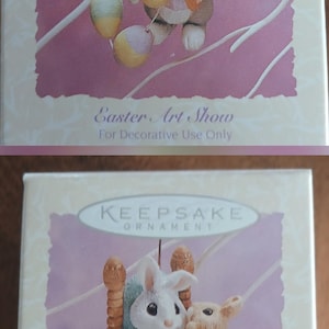 May include: Two Easter-themed Keepsake ornaments. The top ornament features a bunny holding an egg with "1994" on it. The bottom ornament shows two bunnies on a chair. Both ornaments are in boxes with text.