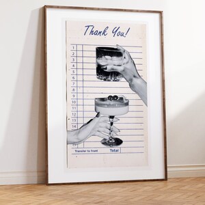 May include: A framed print featuring a vintage-style receipt with the words "Thank You!" at the top. The image shows two hands holding cocktails, one a rocks glass and the other a coupe glass. The print is in a wooden frame.