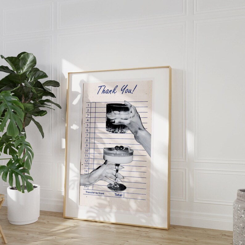 May include: A framed print featuring a vintage-style receipt with the words "Thank You" in script. The image shows two hands holding cocktails, one in a rocks glass and the other in a coupe glass. The print is in a gold frame.
