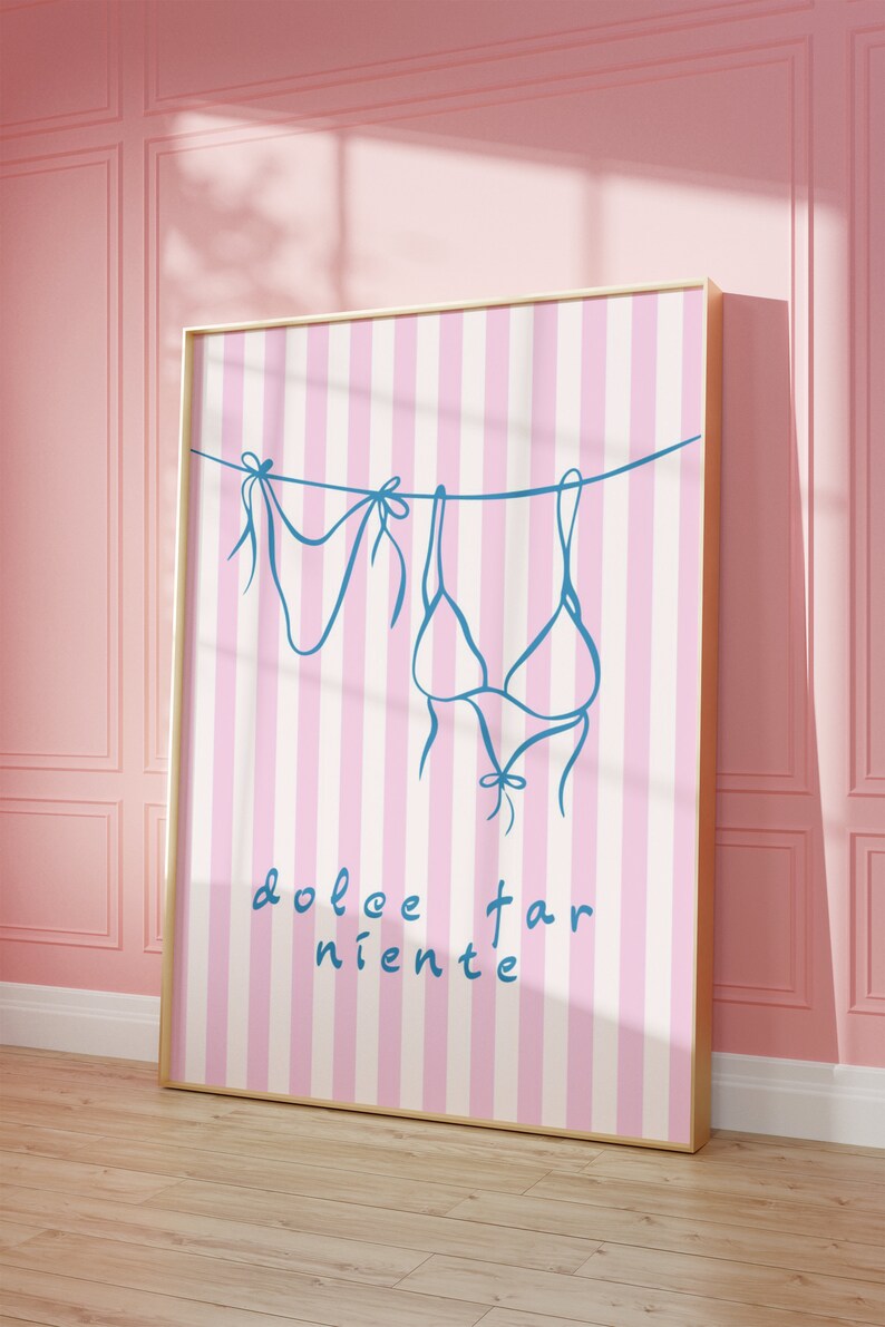 May include: A pink and white striped poster with a blue outline of a bikini hanging on a clothesline. The text "dolce far niente" is written in cursive at the bottom of the poster.