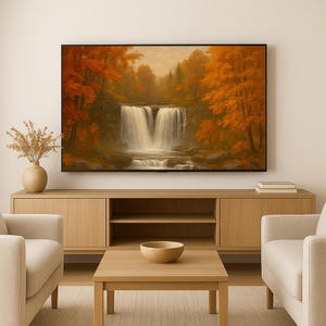 May include: A large framed artwork depicting a waterfall scene surrounded by trees with vibrant orange and red foliage. The artwork is displayed above a light wood cabinet with a matching coffee table and two cream-colored armchairs.