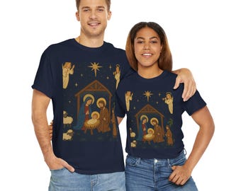 May include: Navy blue t-shirts featuring a Nativity scene with Mary, Joseph, and baby Jesus in a manger. The design includes angels, stars, and sheep. The shirts are worn by a man and a woman.