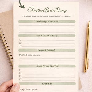 May include: A Christian Brain Dump notepad with prompts for reflection. The notepad includes sections for listing priorities, prayers, and gratitude. A gold pen rests beside the notepad. The text "1 PAGE INCLUDED" is at the top.