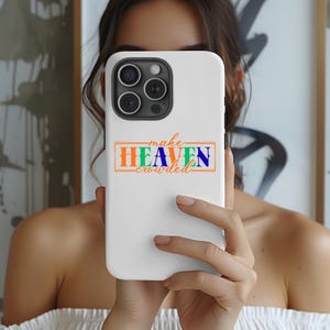 Könnte beinhalten: Weißes Handycase mit dem Text "make HEAVEN crowded" in Orange, Grün und Blau. Das Handycase hat ein Kameramodul mit drei Linsen. Das Case wird vor einer Person hochgehalten.