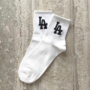 May include: A pair of white socks with black "LA" lettering on each sock.