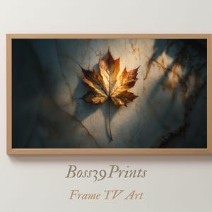 Op de afbeelding: Een ingelijste print met een close-up van een esdoornblad. Het blad heeft een kleurenpalet van goudgeel tot diepbruin, tegen een marmerachtige achtergrond. De lijst is lichtbruin. De tekst "Boss39 Prints Frame TV Art" staat onderaan.