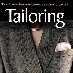 May include: A book cover titled Tailoring: The Classic Guide to Sewing the Perfect Jacket. The image features a textured charcoal gray blazer with a white pocket square and a metallic silver collar, set against a dark background.