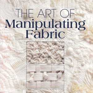 May include: A book cover titled THE ART OF Manipulating Fabric in dark blue text. The background features off-white fabric with various textures, pleats, and gathers. Two rectangular insets show close-ups of smocking and woven fabric techniques.