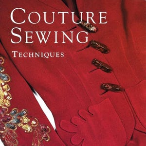 Può includere: Un indumento rosso intenso con il testo bianco Couture Sewing Techniques. Il capo presenta quattro chiusure a levetta marrone scuro e una manica decorata con intricati ricami di paillettes dorate e multicolori in un motivo floreale.