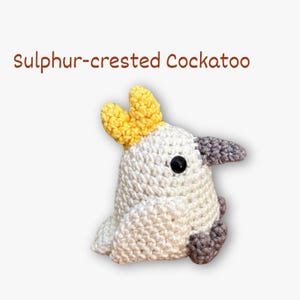 May include: A crocheted Sulphur-crested Cockatoo bird. The bird is white with a yellow crest, grey beak, and black eyes. The text "Sulphur-crested Cockatoo" is written in brown above the bird.