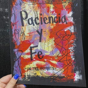 May include: Abstract art print with the words "Paciencia Y Fe" in black over a colorful background of red, orange, purple, and yellow brushstrokes. The print also includes musical notes and the text "IN THE HEIGHTS".