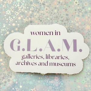 May include: A white die-cut sticker featuring the purple text 'women in G.L.A.M. galleries, libraries, archives and museums'. The sticker has a smooth, rounded shape and is displayed against a background covered in a holographic star pattern.