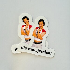 May include: Two die-cut stickers featuring a man in a red and white shirt, with the text "it's me...jessica!". The man is smiling and posing with his arms crossed. The stickers are white with a light gray background.