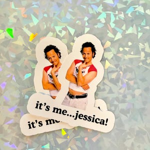 May include: Two stickers featuring a man in a red and white shirt, with the text "it's me...jessica!" printed on them. The stickers are white with a die-cut edge, and the background is a holographic, iridescent pattern.