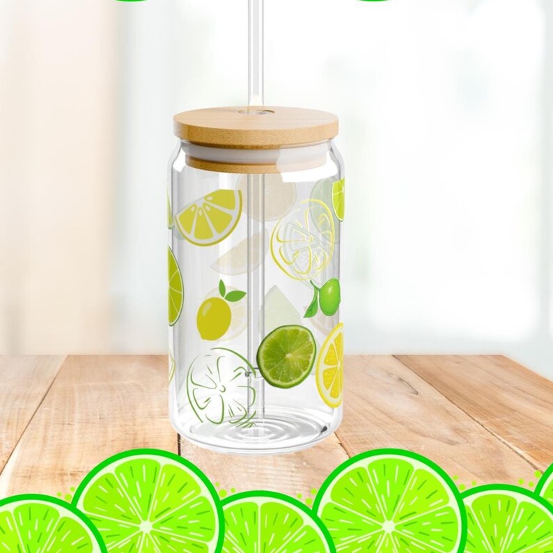May include: A clear glass tumbler with a cylindrical shape, featuring a pattern of yellow lemon and green lime slices. The glass includes a light-colored wooden lid with a central hole and a clear glass straw inserted through the top opening.