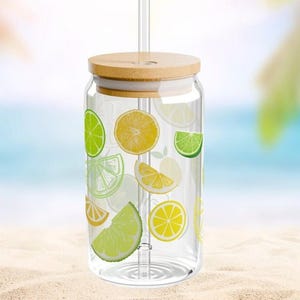 May include: A clear glass tumbler with a bamboo lid and a glass straw, featuring a colorful pattern of yellow lemon slices and green lime slices printed on the exterior. The cylindrical glass has a wide mouth and a flat base for stability.