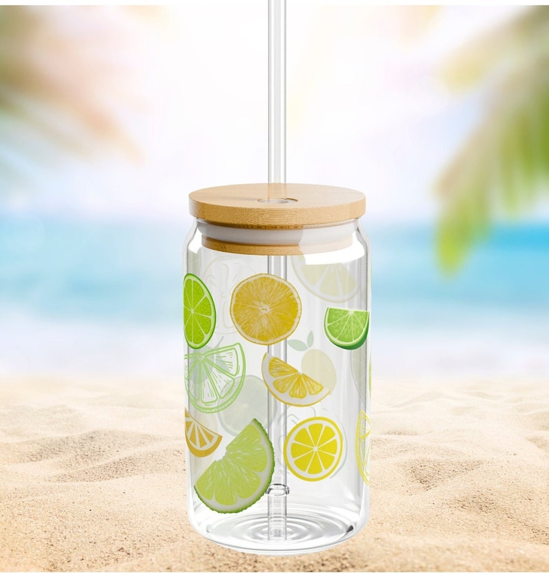 May include: A clear glass tumbler with a cylindrical shape, featuring a pattern of yellow lemon and green lime slices. The glass includes a light-colored bamboo lid with a central hole and a straight, transparent glass straw inserted through the top.