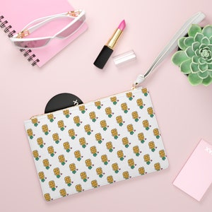 May include: White zippered pouch with a repeating pattern of yellow pineapples with green tops and pink hearts. The pouch has a gold zipper and a white strap.
