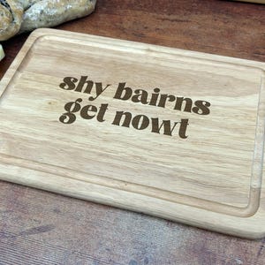 May include: A wooden chopping board with the text "shy bairns get nowt" engraved on it.