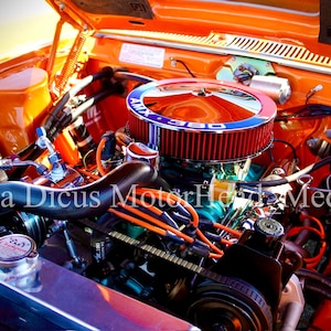 Puede incluir: Primer plano de un motor de coche naranja con un filtro de aire rojo y mangueras negras. El motor está etiquetado como "AMX 380".