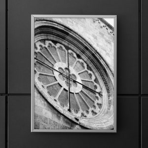 Könnte beinhalten: Schwarzweißfoto eines runden, verzierten Fensters mit geometrischem Muster. Das Fenster ist in eine Steinmauer eingelassen.