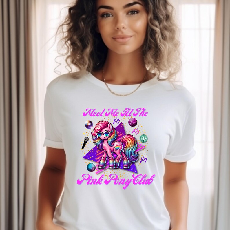 May include: White t-shirt with a pink, purple, and rainbow cartoon pony wearing sunglasses and holding a microphone. The text "Meet Me At The Pink Pony Club" is printed on the shirt.
